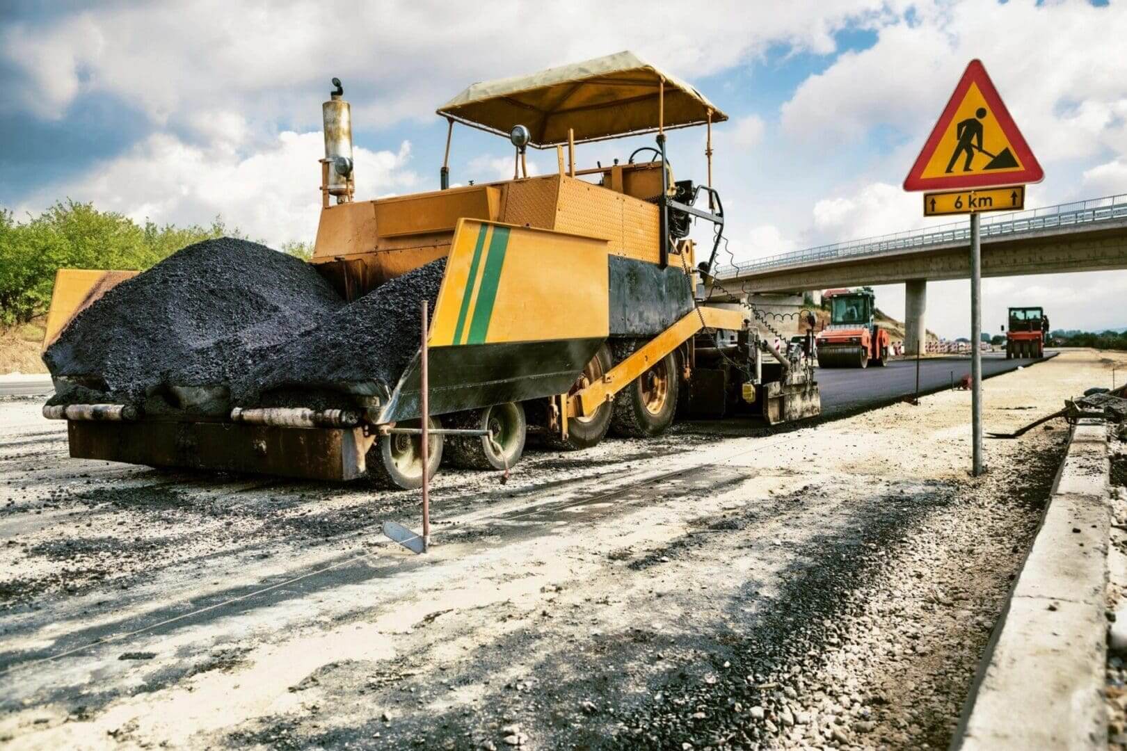 Asphalt paving machine laying road surface on construction site.