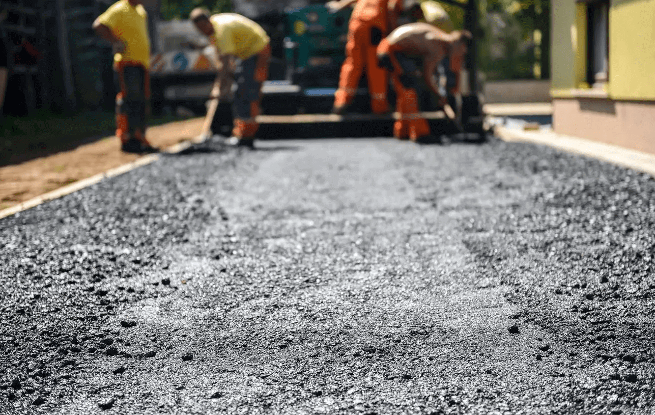 Workers paving a road with fresh asphalt.