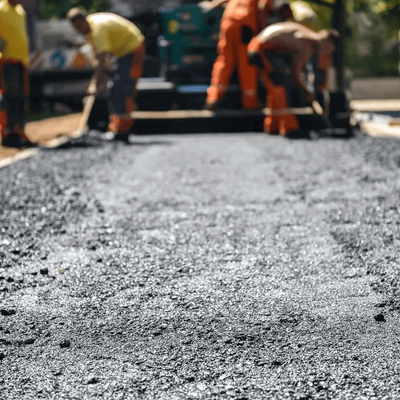 Workers paving a road with fresh asphalt.